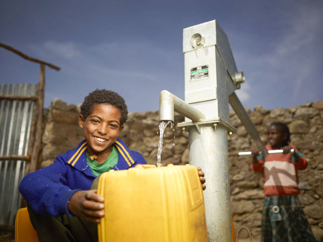 Youth filling up from a newly installed well from Charity: Water